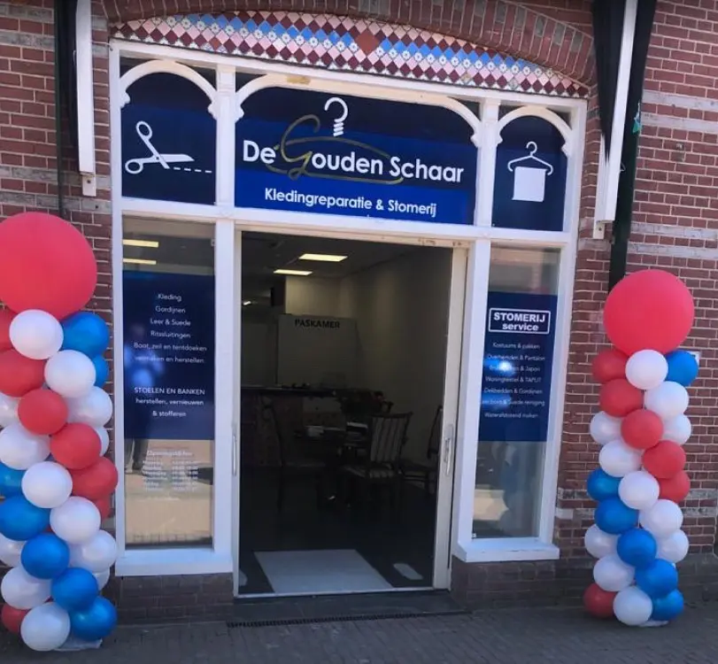 De ingang van De Gouden Schaar met rood-wit-blauwe ballonnen aan weerszijden van de deur